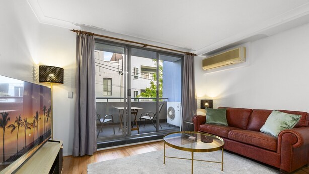 Una sala de estar moderna con una mesa de centro de vidrio, un sofá de cuero rojo y un televisor de pantalla plana.