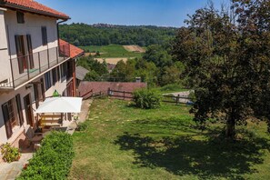 A two-story building with a balcony, a small patio with outdoor furniture, and a view of a green landscape. - Casa dël canton (Viale)