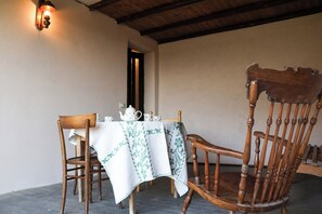A dining table with a tablecloth, a wooden chair, and a wall-mounted light fixture. - Casa dël canton (Viale)