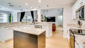 A modern kitchen with a central island, built-in appliances, and a large window.