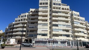 Un edificio a più piani con balconi, un ristorante chiamato "Heladera" al piano terra e un'auto parcheggiata davanti.