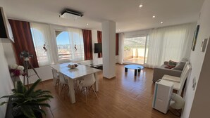Un'ampia zona giorno con tavolo da pranzo, divano e balcone con vista.