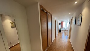 Un corridoio con pavimento in legno, pareti bianche e una porta scorrevole.
