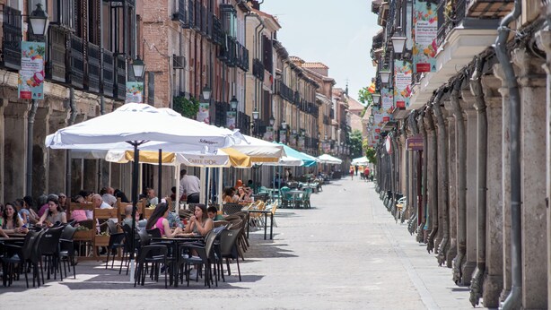 Una strada fiancheggiata da caffè all'aperto, tavoli e sedie, con edifici su entrambi i lati.