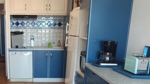 Una cucina compatta con mobili azzurri, un frigorifero bianco, una moka e un tostapane vintage.
