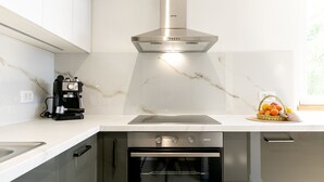 A modern kitchen with a built-in oven, a coffee machine, and a stainless steel range hood.