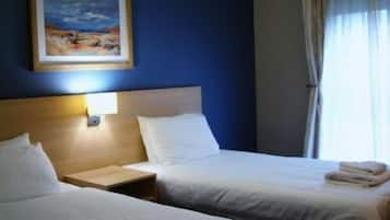 A hotel room with two beds, a nightstand, a painting on the wall, and a window with curtains.