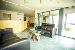 A modern reception area with a glass coffee table, leather sofas, and a wooden reception desk.
