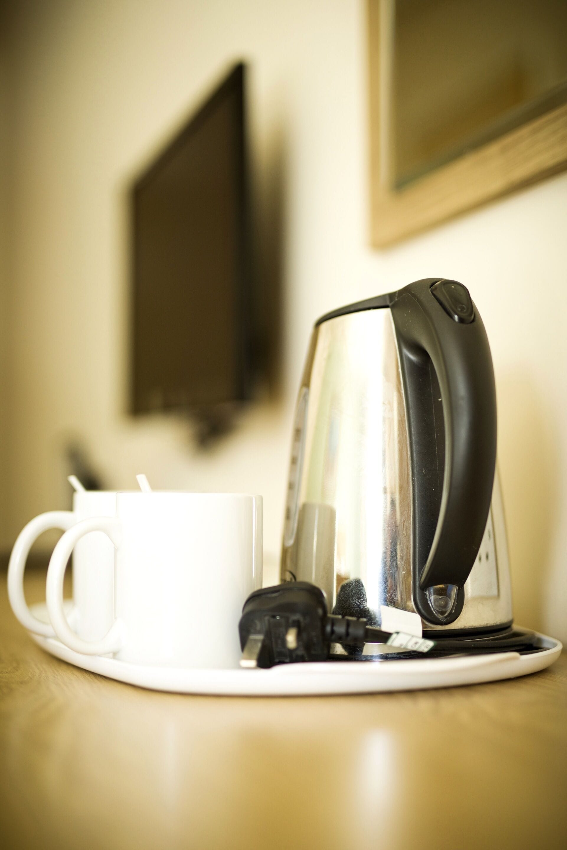 Une machine à café est posée sur une table, à côté de deux tasses blanches.