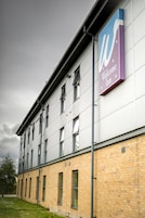 A modern building with a 'Welcome Inn' sign, featuring a simple facade with multiple windows and a brick lower section.