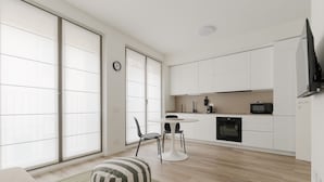 A modern kitchen with white cabinets, a dining table, chairs, and a TV mounted on the wall. - GuestHost - Modern 40 mq studio apartment located on the first floor of a residential complex with a lift.The property is located within the Moscova district, a well-known central area of ​​Milan, the hub of Milanese nightlife and aperitifs.The area  (Milan)