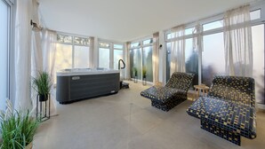 A spacious room with a hot tub, two patterned lounge chairs, and large windows with sheer curtains. - Apartamenty Sun & Snow Welle Resort (Grzybowo)