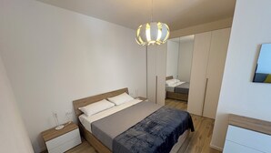 Une chambre à coucher comprenant un lit, des tables de chevet, une armoire et un miroir.