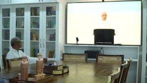 Une salle de conférence équipée d’un grand écran, d’un pupitre et où une personne prend la parole.