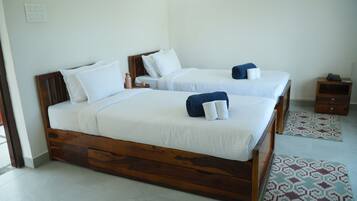 A hotel room with two wooden beds, white bedding, and a small wooden nightstand with a phone.