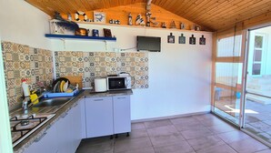 A kitchen with a tiled backsplash, a microwave, a sink, and cabinets. There is a window with a view of the outside. - EPAT  (Limanu)