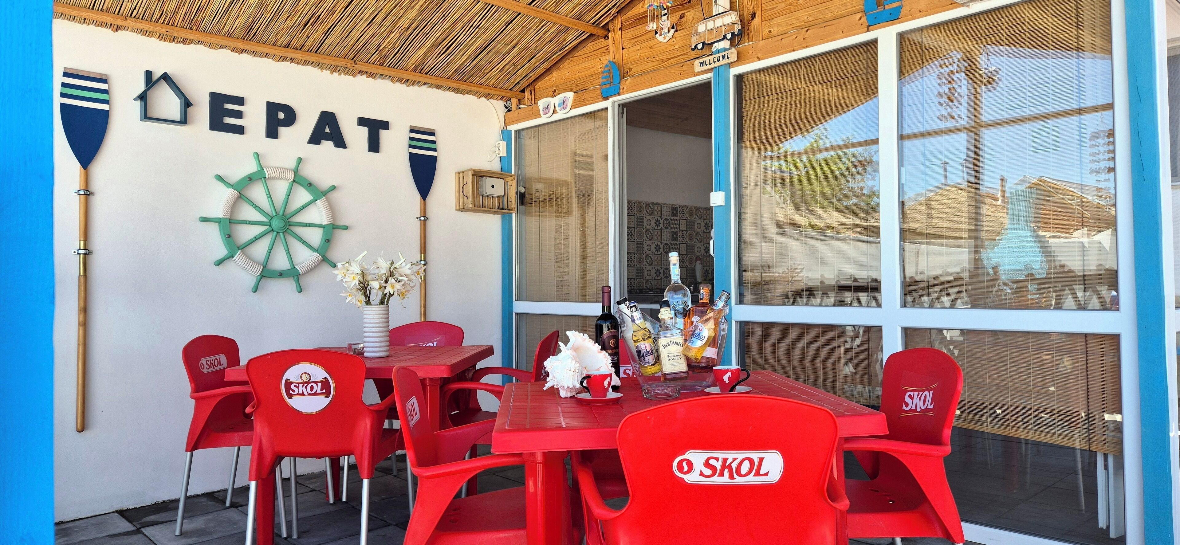 A restaurant with red plastic chairs and tables, a wooden ceiling, and nautical decorations.