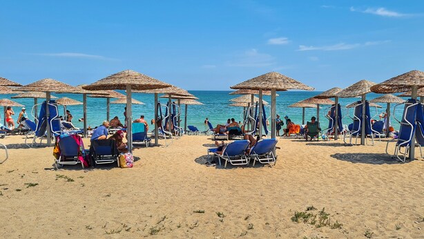 A beach with sun umbrellas and lounge chairs, a clear sky, and the ocean in the background. - EPAT  (Limanu)