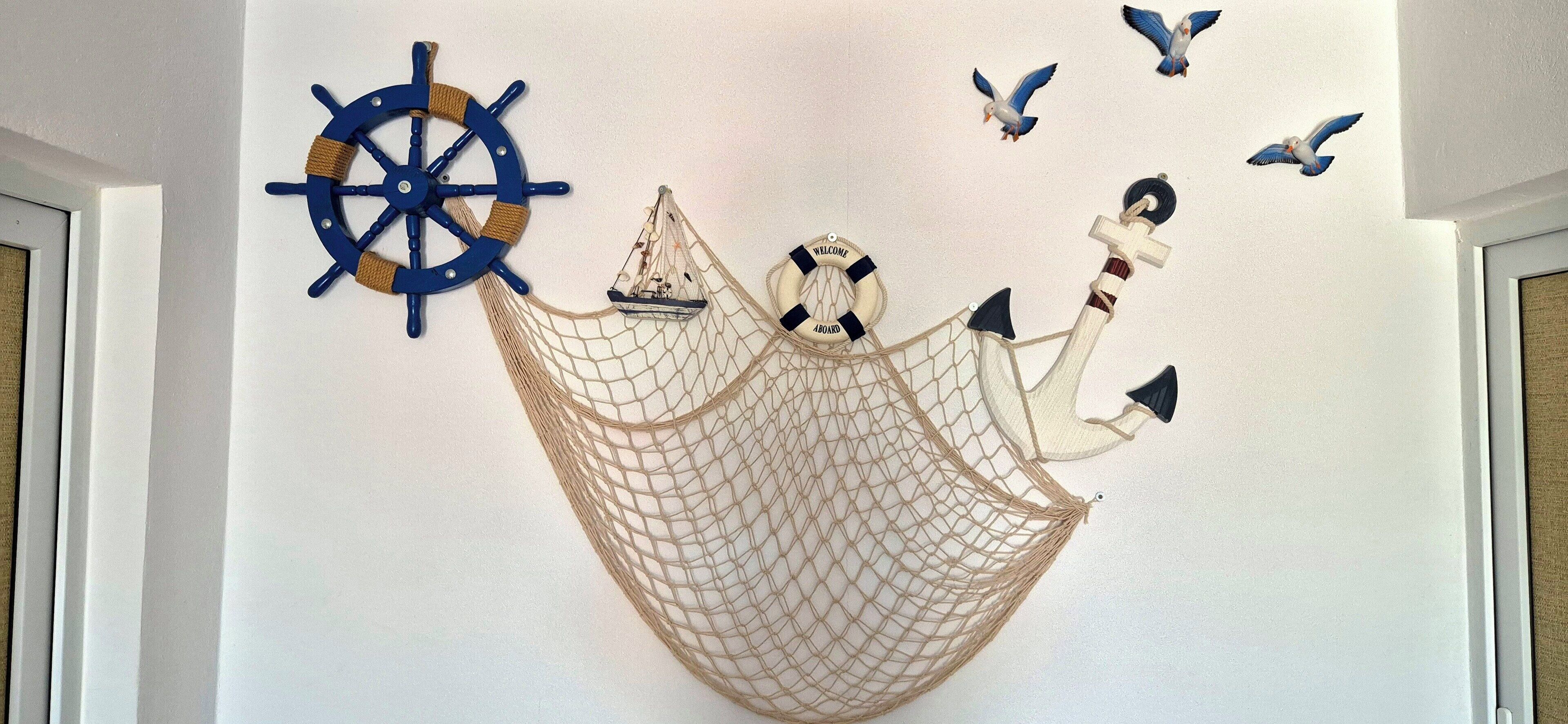 A wall decoration with a ship's wheel, a sailboat, and birds.