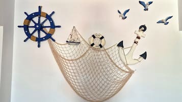 A wall decoration with a ship's wheel, a sailboat, and birds.