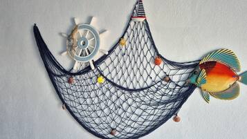 A hammock with a net, a ship's wheel, and a fish decoration on a textured wall.