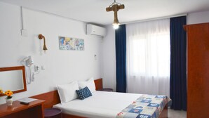 A hotel room with a bed, a desk with a chair, a wardrobe, and a window with curtains. - EPAT  (Limanu)