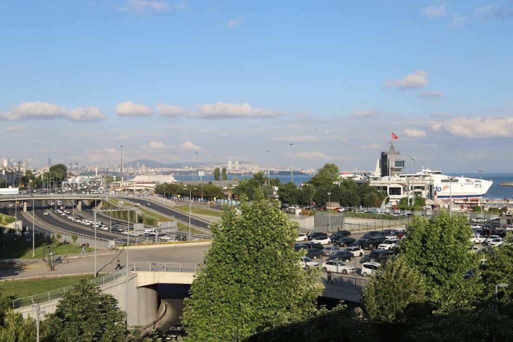 Une vue urbaine comprenant une autoroute, un pont et un grand bâtiment sur lequel flotte un drapeau.