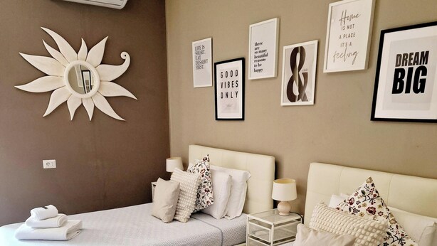 A hotel room with two beds, a sun-shaped mirror, and motivational wall art. - Beautiful apartment recently renovated and complete with everything (Roma)
