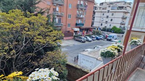 A balcony with a railing, a view of parked cars, and a building with balconies in the background. - Beautiful apartment recently renovated and complete with everything (Roma)