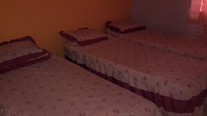 Una habitación con tres camas individuales, cada una con una colcha y almohadas estampadas con motivos florales.
