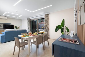 Ein modernes Wohnzimmer mit Essbereich, einer Couch, einem Fernseher und einer großen Pflanze.