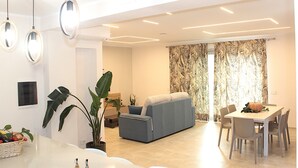 Un salon moderne avec un canapé, une table à manger, des chaises et des luminaires suspendus.