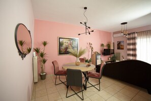 A dining area with a round table, chairs, a mirror, and a painting on the wall. - Experience relaxed coastal living (Kalamata)