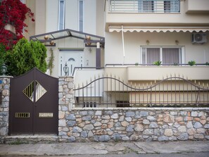 A gated entrance with a stone wall, a metal gate, and a building with balconies and windows. - Experience relaxed coastal living (Kalamata)