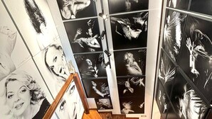 Eine Treppe mit hölzernem Geländer und einer Wand, die mit Schwarz-Weiß-Fotos verziert ist.