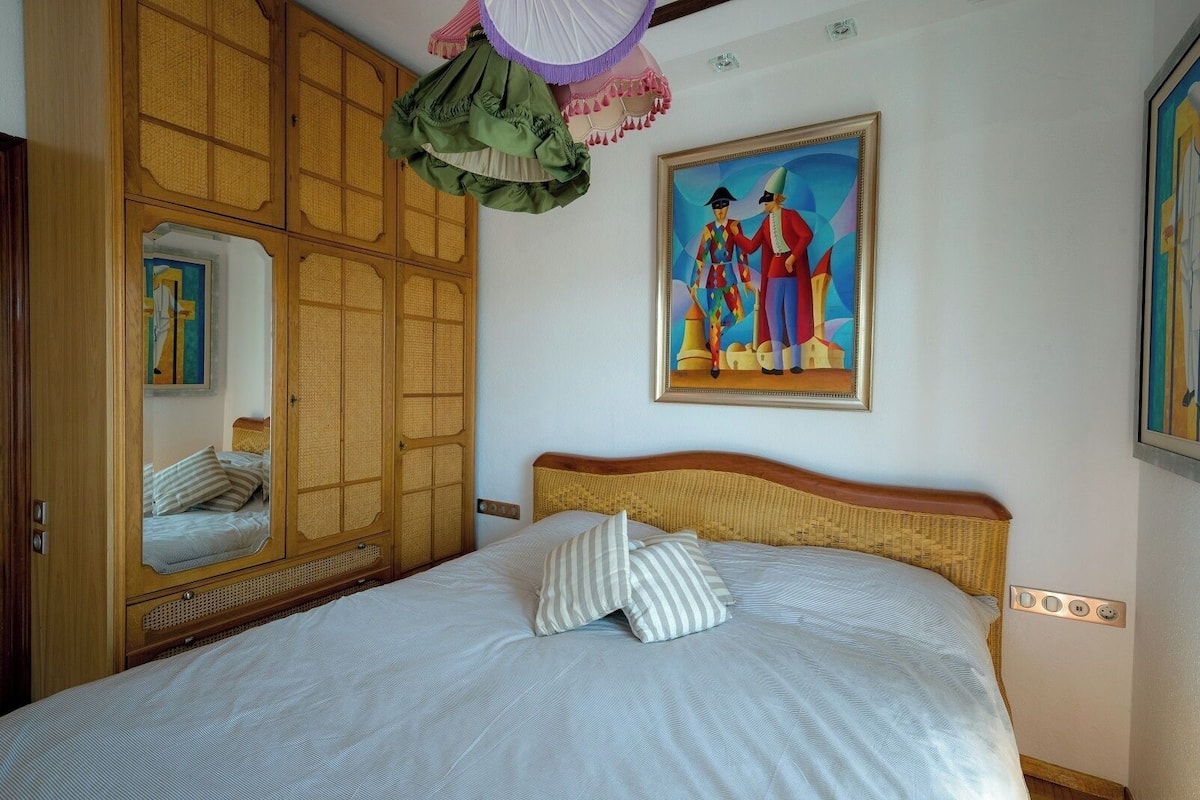 Une chambre à coucher avec un lit, un miroir, un tableau et une armoire en bois.