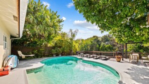 Ein Garten mit Swimmingpool, Liegestühlen und einer Holzterrasse.