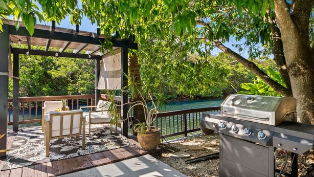 Eine Terrasse im Freien mit Grill, Sitzgelegenheiten und Blick auf ein Gewässer.