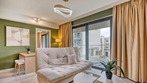 Un soggiorno moderno con divano, tavolino da caffè e vista sulla città attraverso ampie finestre.