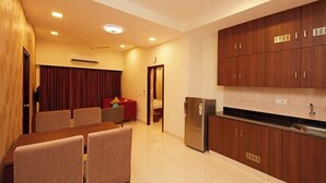 Una cocina moderna con armarios de madera, un refrigerador empotrado y una zona de comedor con mesa y sillas.