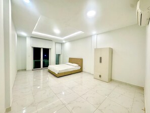 A spacious bedroom with a large bed, a wardrobe, and a sliding glass door leading to a balcony.