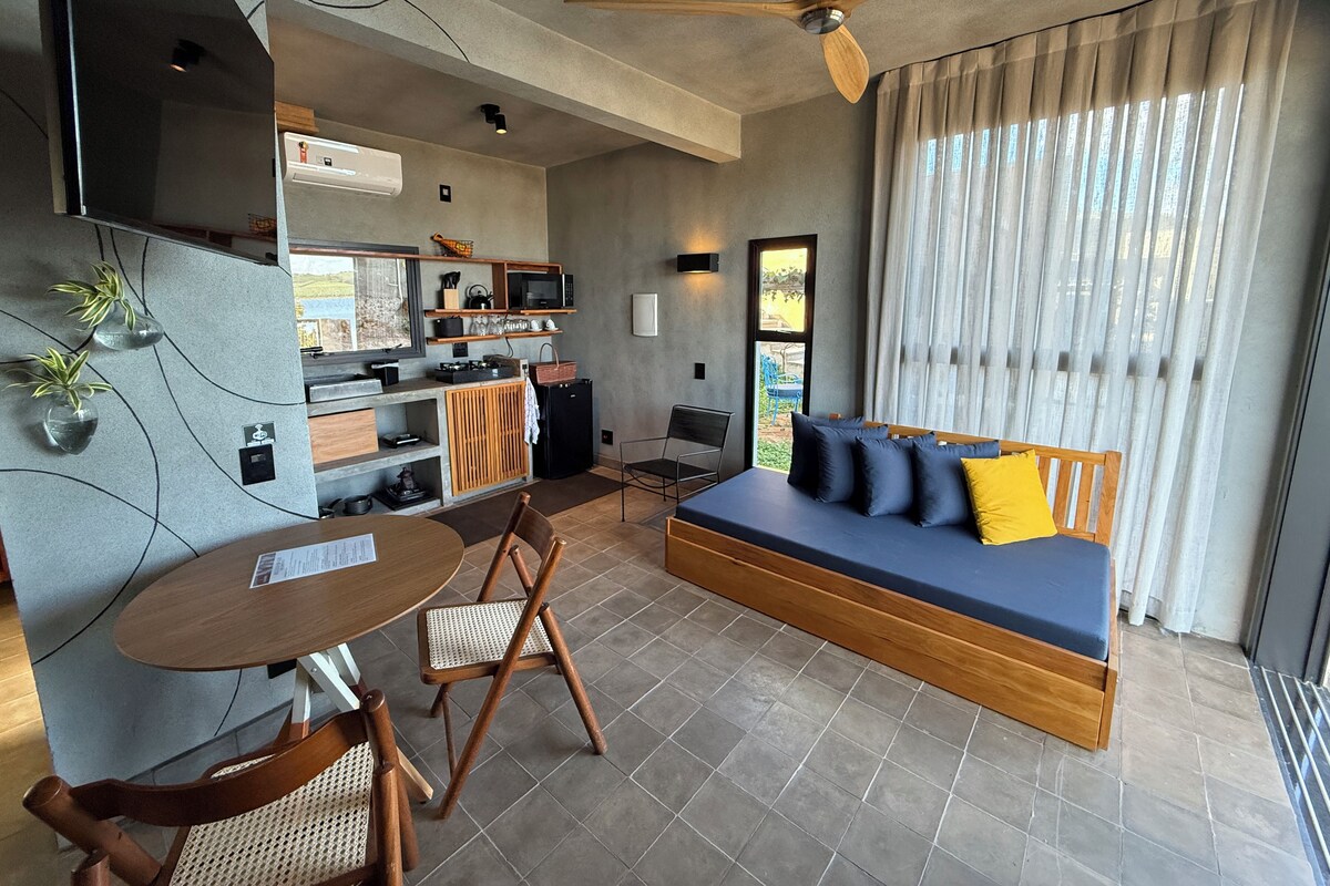 A modern living space with a sofa, dining table, chairs, kitchenette, and a ceiling fan.