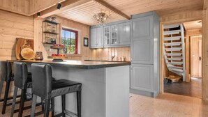 A kitchen with wooden walls, a bar area with stools, and a staircase.