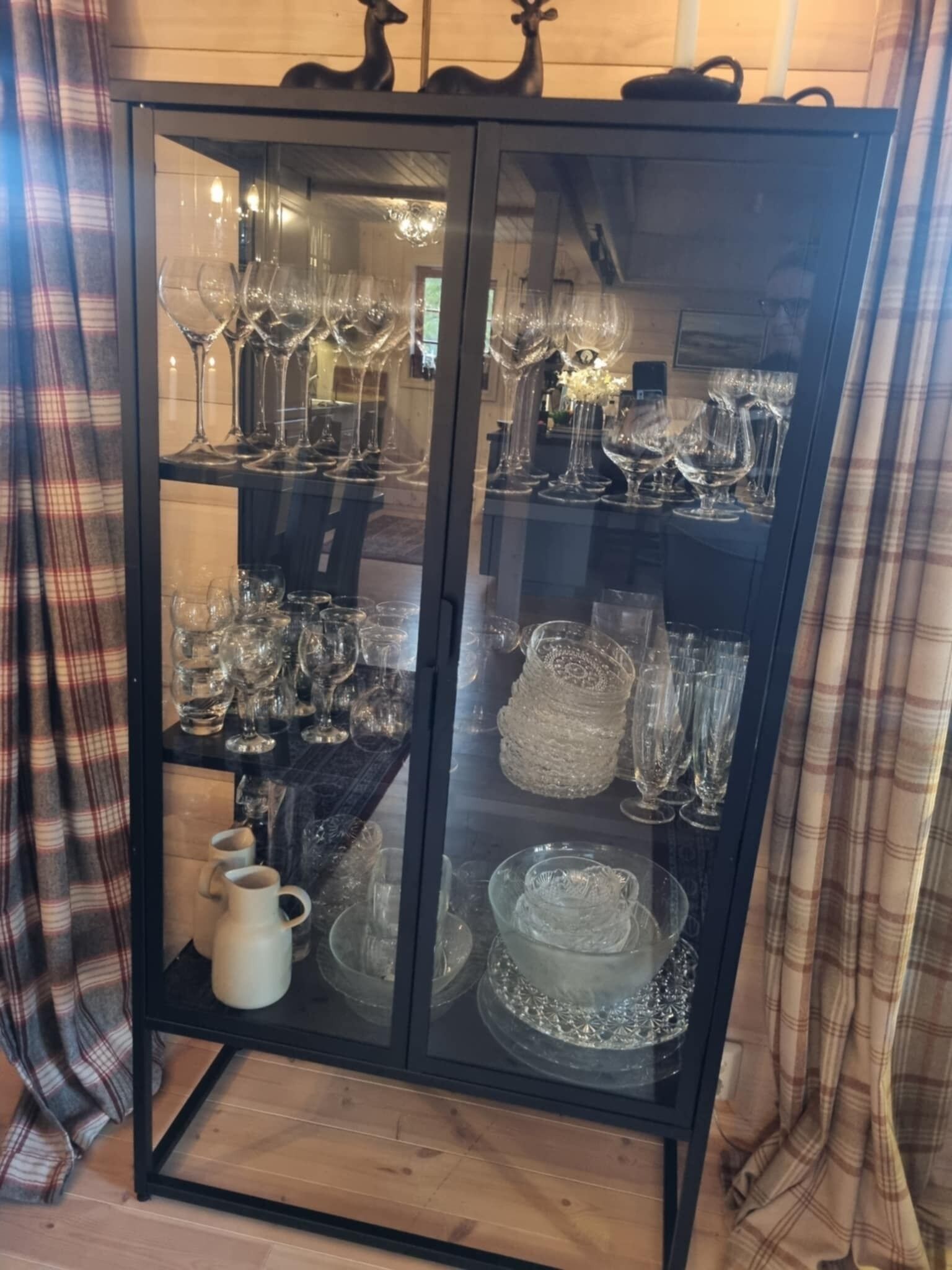 Un meuble vitré contenant divers objets en verre et un pichet blanc.