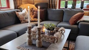 A cozy living room with a sofa, a coffee table with candles, a potted plant, and a rug.