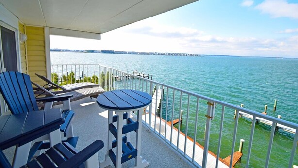 A balcony with a view of the water, a table, and two chairs. - Thunder Island 13a 2 Bedroom Condo (Ocean City)