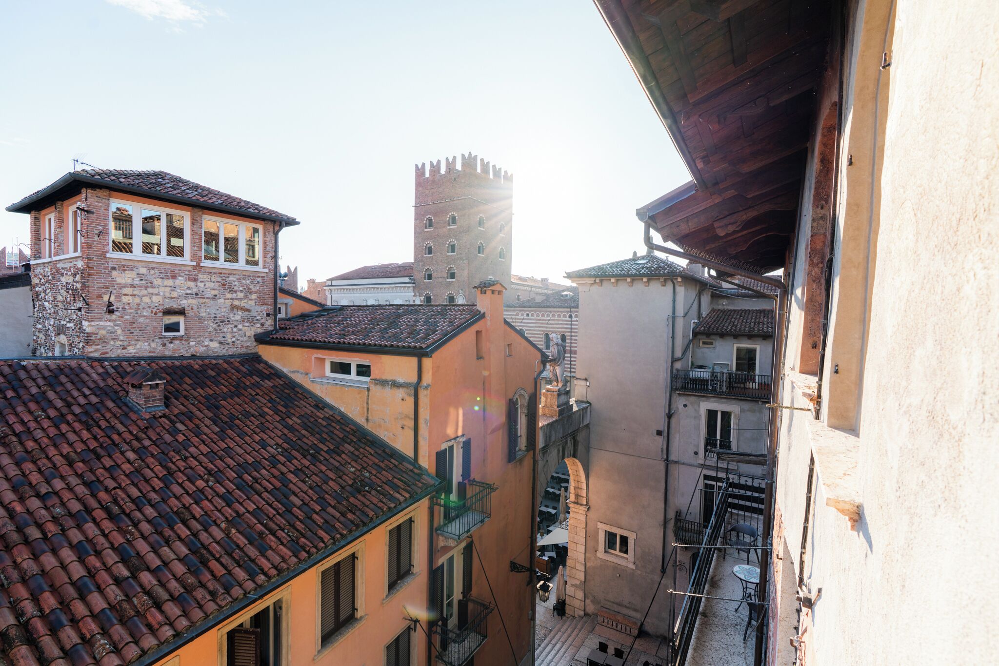 A narrow street with buildings, including a tower and a building with a tiled roof.
