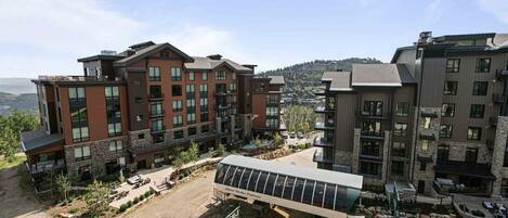 A modern multi-story building with a mix of brick and stone facades, large windows, and balconies.