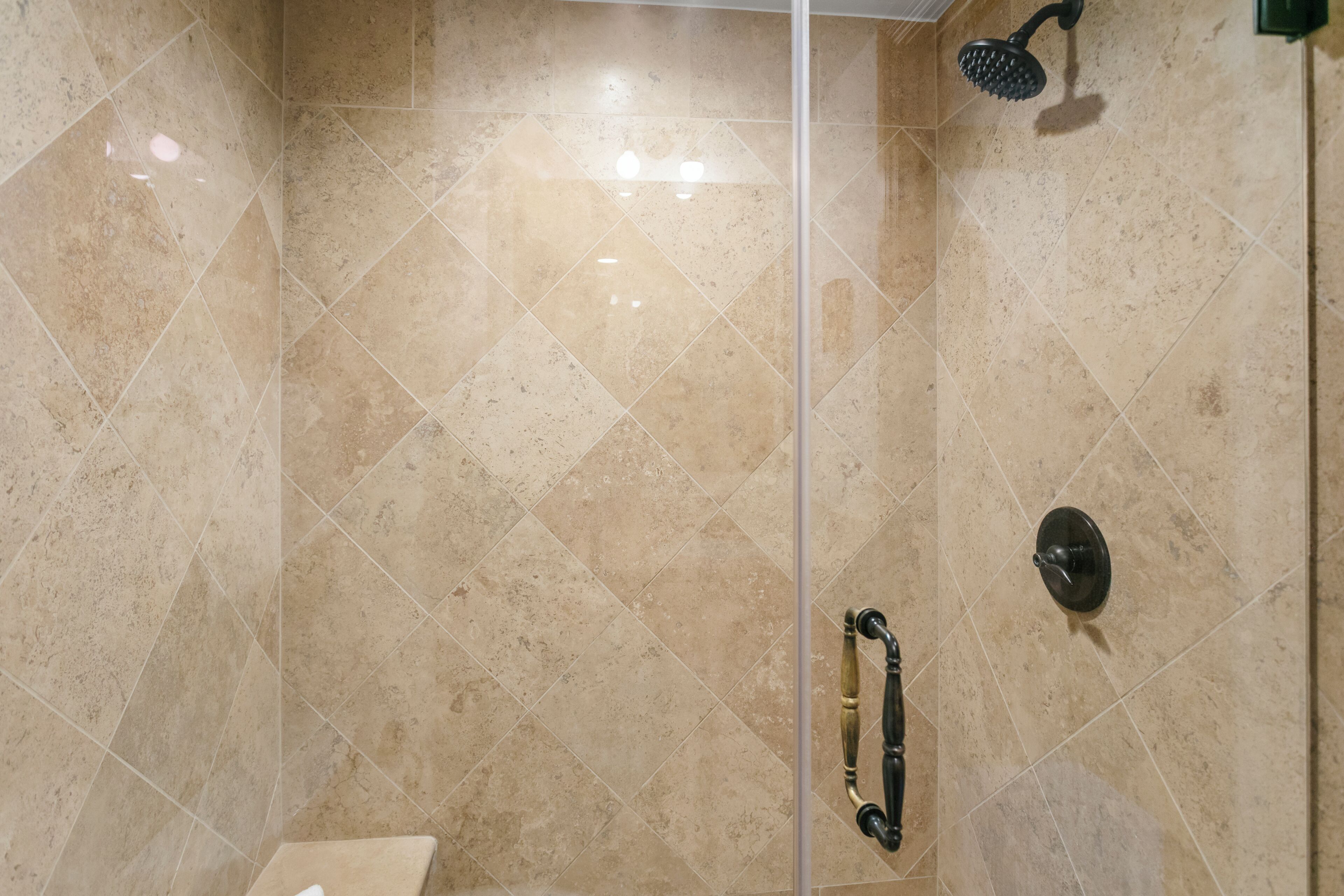 Un baño con paredes de azulejos color beige y zona de ducha.