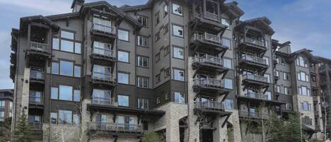 A multi-story building with balconies and a stone facade.